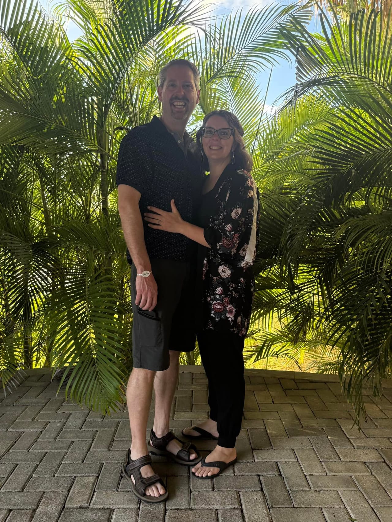 Dave and Cassie standing together among the palms