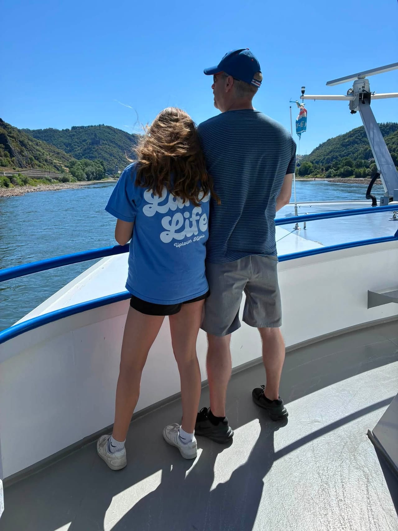 Dave and one of the girls at the bow railing, backs to the camera, looking out at the Rhine Gorge