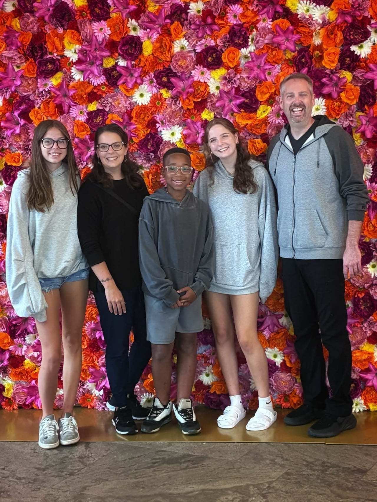 All five of us in front of a bright flower wall in Amsterdam