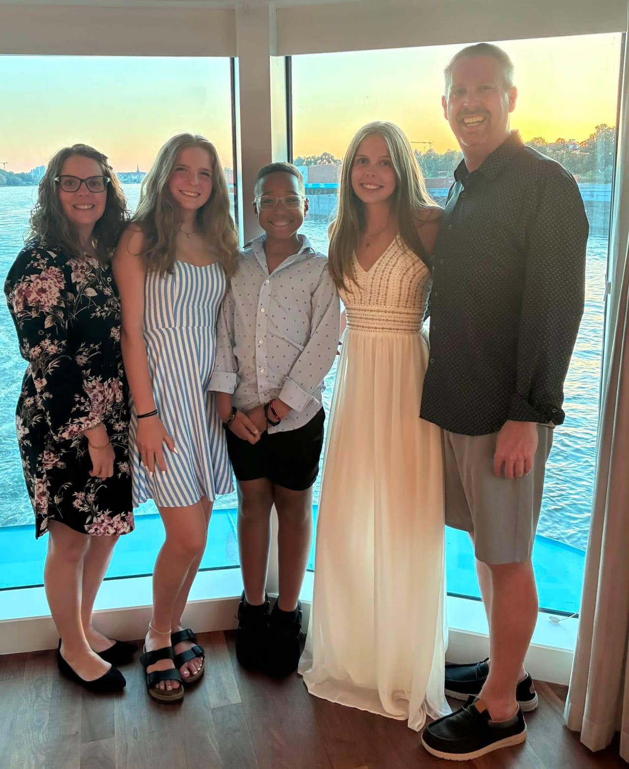 All five of us dressed up by the ship’s windows, with the river and sunset behind